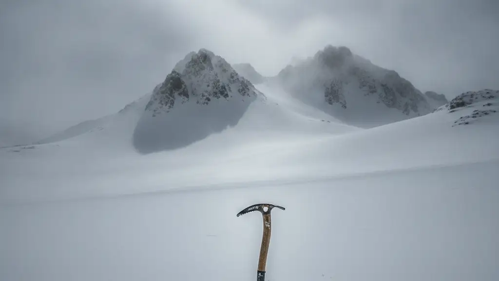 An ice axe stuck in a vast, empty snowfield on a misty mountain.