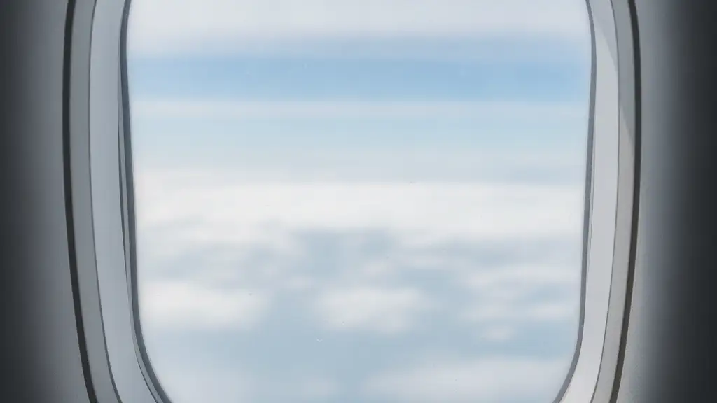 Airplane window with a subtle atmospheric distortion, showing blurred clouds outside.