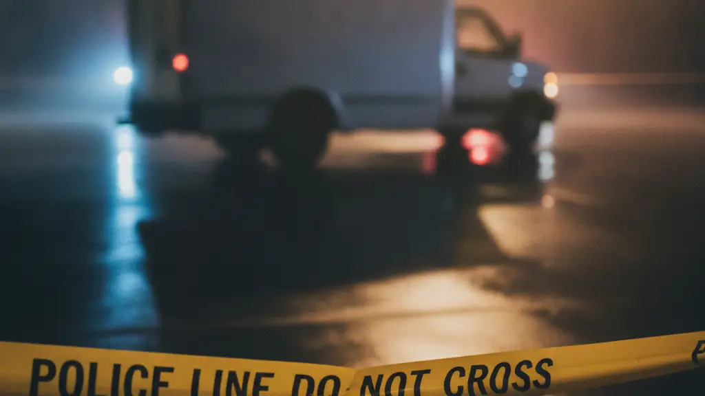 Police tape in foreground, blurred emergency lights and van in background.