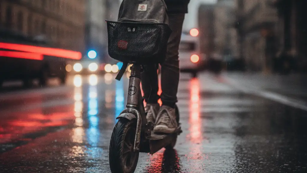 Silhouette of child on e-scooter, emergency lights reflecting on wet street.