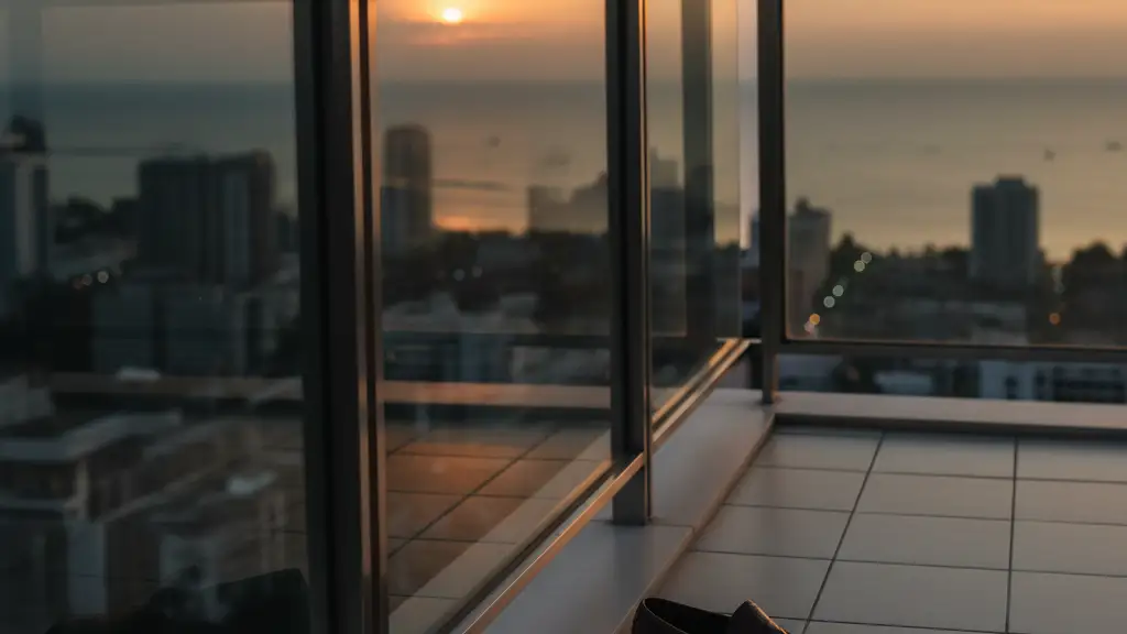 A luxury high-rise balcony at dusk overlooking a blurred coastal city skyline.