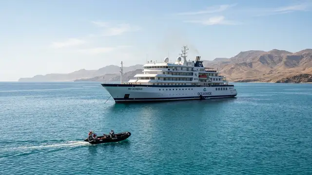 Expedition cruise ship 'MV Hondius' anchored off a distant coast, a medical zodiac approaching.