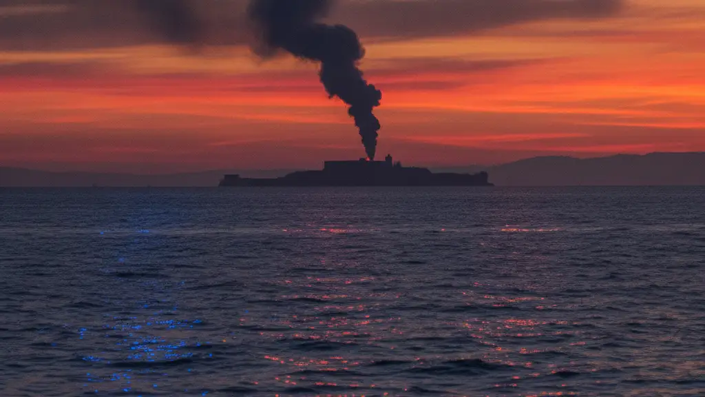 Distant smoke plume over San Francisco Bay at sunset, Alcatraz silhouette, emergency lights reflection.