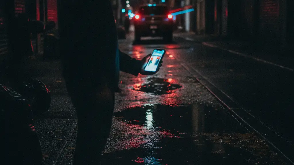Blurred silhouette reflected in a puddle, emergency lights, smartphone glow.