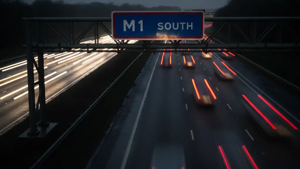 Rain-slicked motorway sign for M1 South with blurred car lights in background.