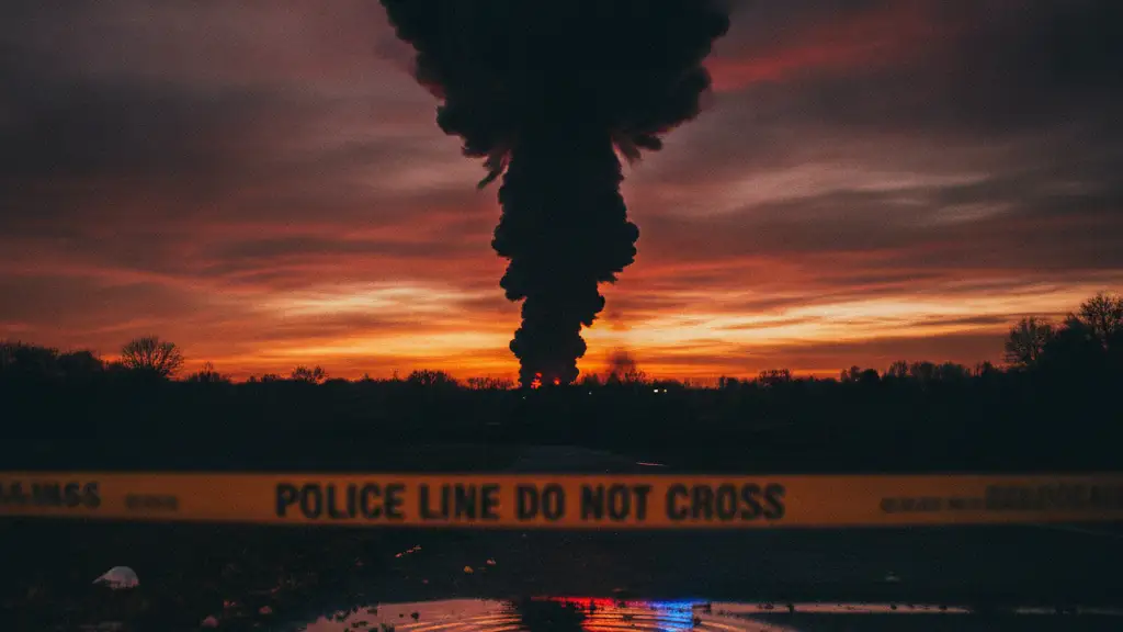 Thick smoke plume against a fiery sky, with police tape in the foreground.