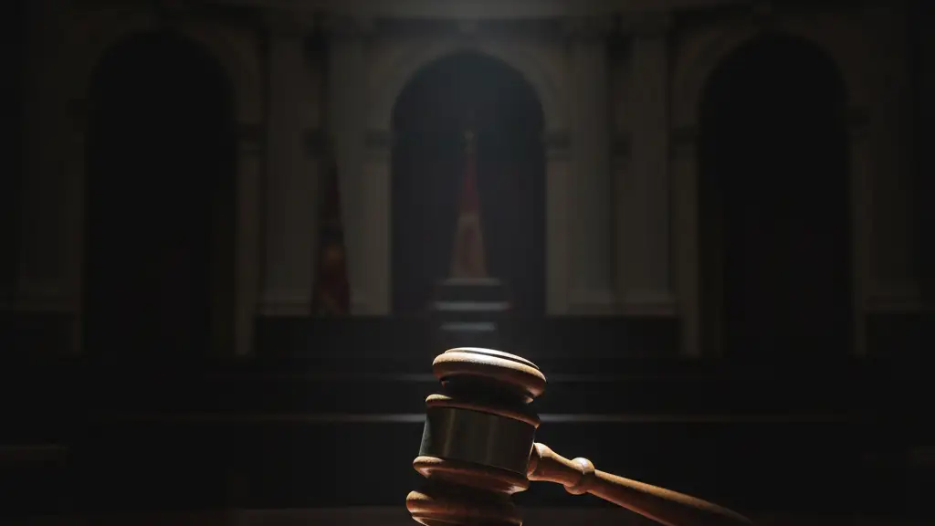 A lone, heavy wooden gavel on a polished mahogany desk, dramatically lit.