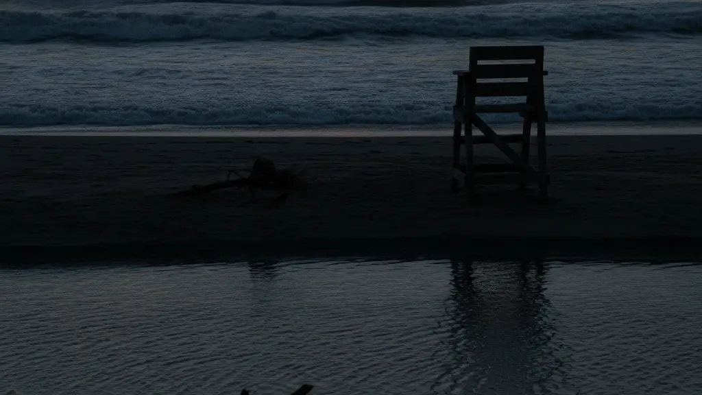 A lone lifeguard chair silhouetted against a turbulent sea at dusk.