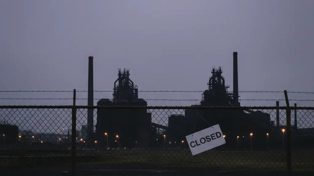 The silhouette of a dormant steelworks factory against a dark twilight sky in South Wales.
