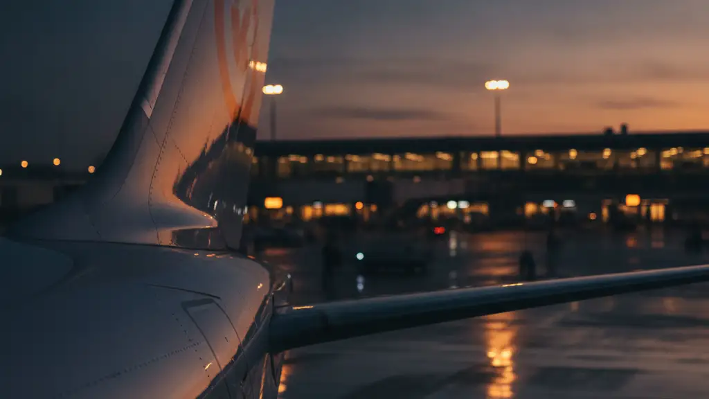 Close-up of an airplane tail fin with a subtle orange logo at dusk.