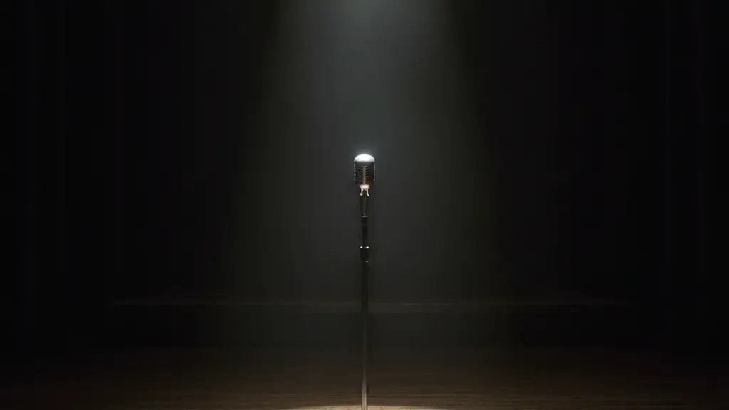 Empty concert stage with a single microphone stand under a spotlight.