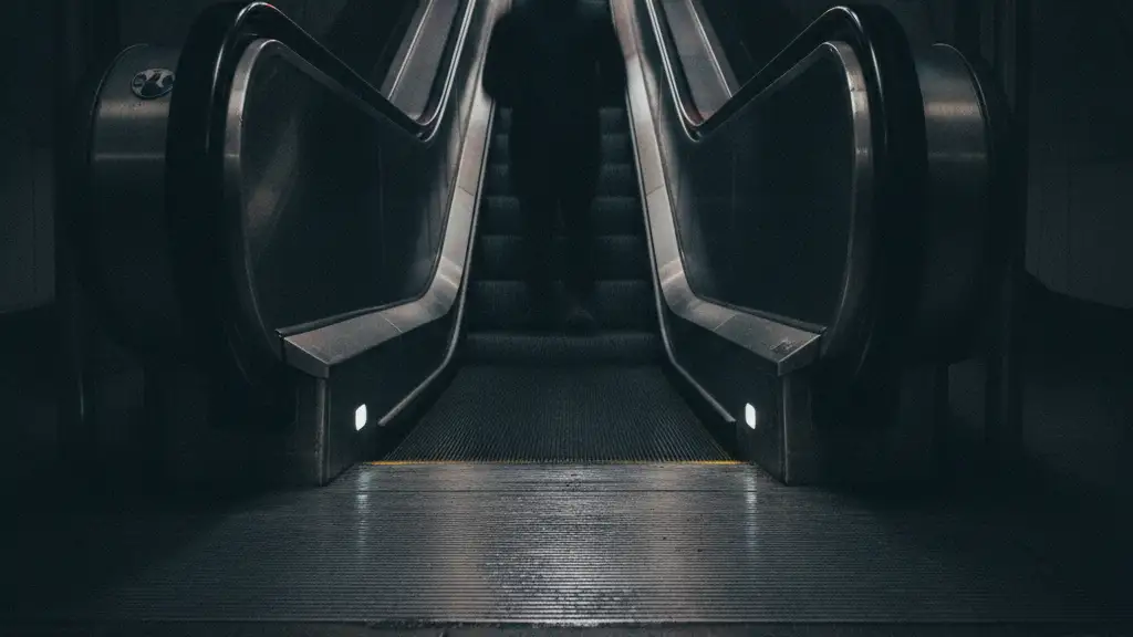 Blurred figure on a London Underground escalator with emergency light reflections.