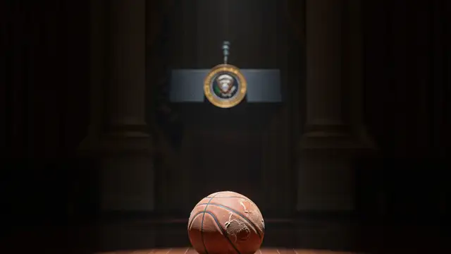 A deflated basketball on a polished floor, presidential seal blurred in background.