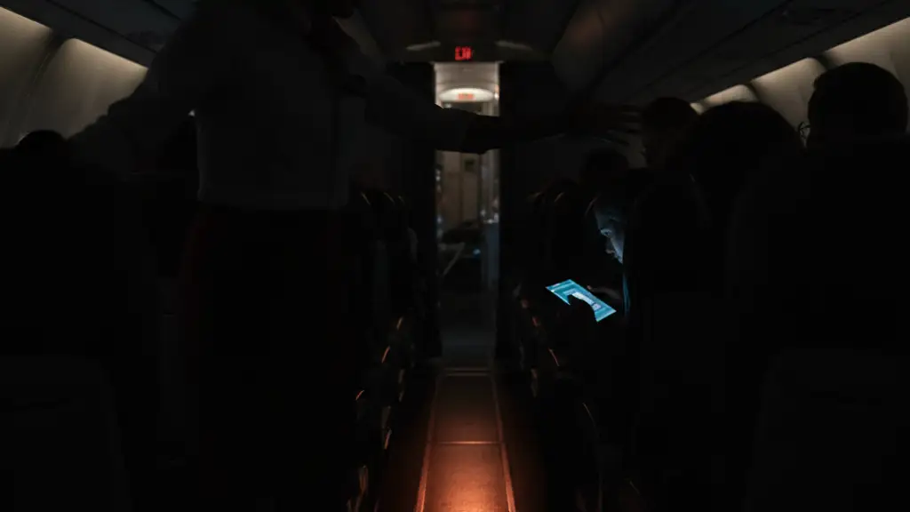 Flight attendant's blurred hand reaching in a dimly lit airplane cabin during an emergency.