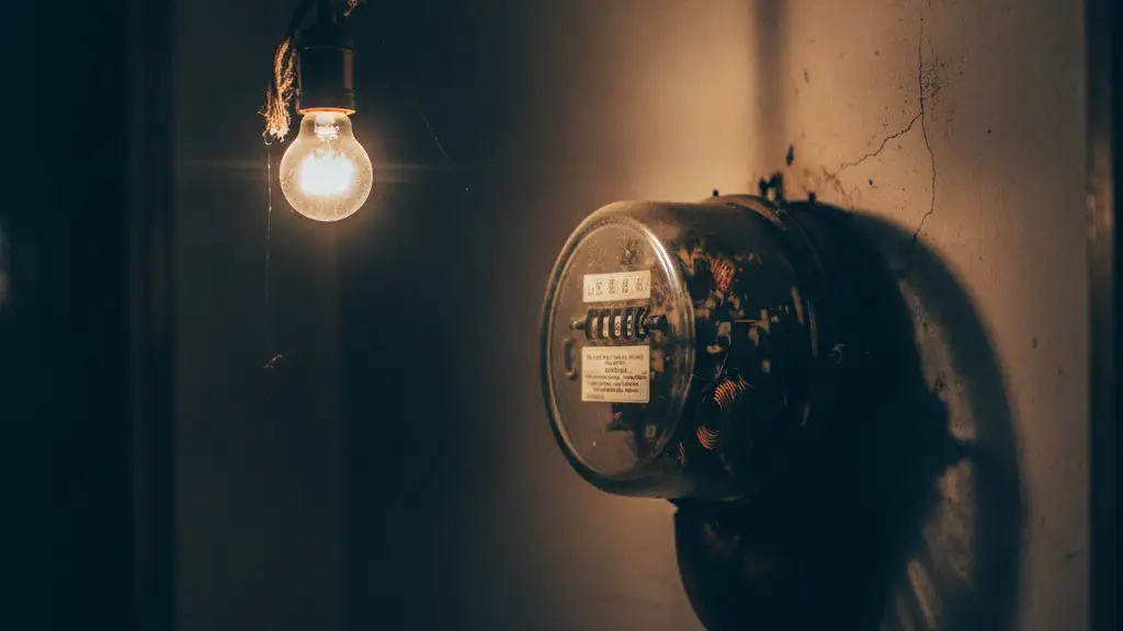 Close-up of a vintage electricity meter with blurred numbers and a single dim lightbulb.