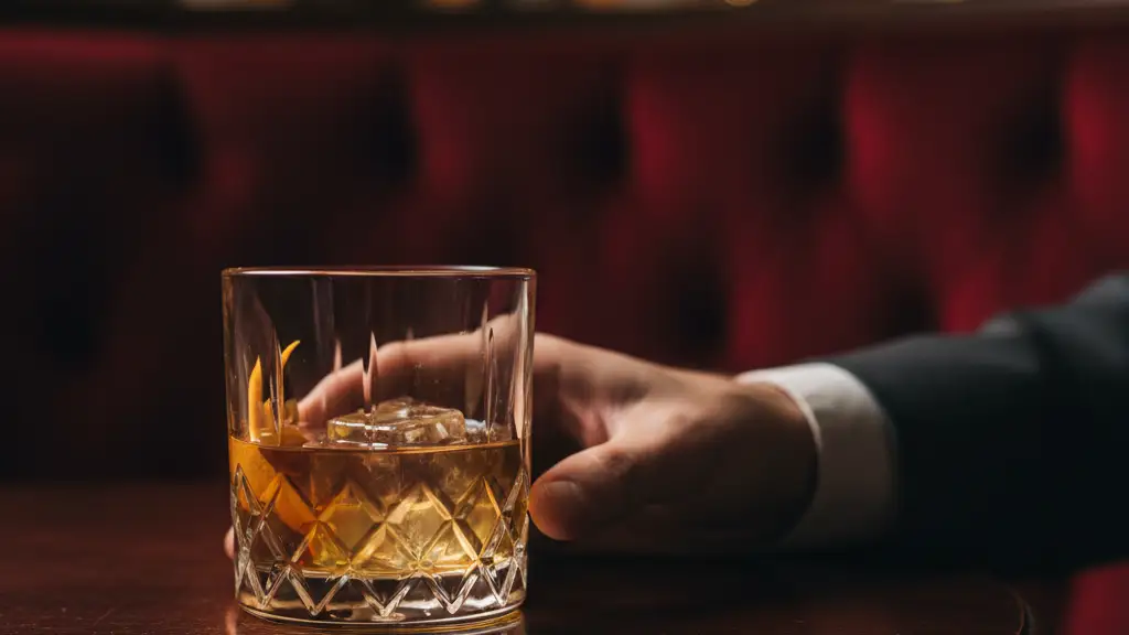 A crystal cocktail glass on a dark table in a dimly lit luxury lounge.