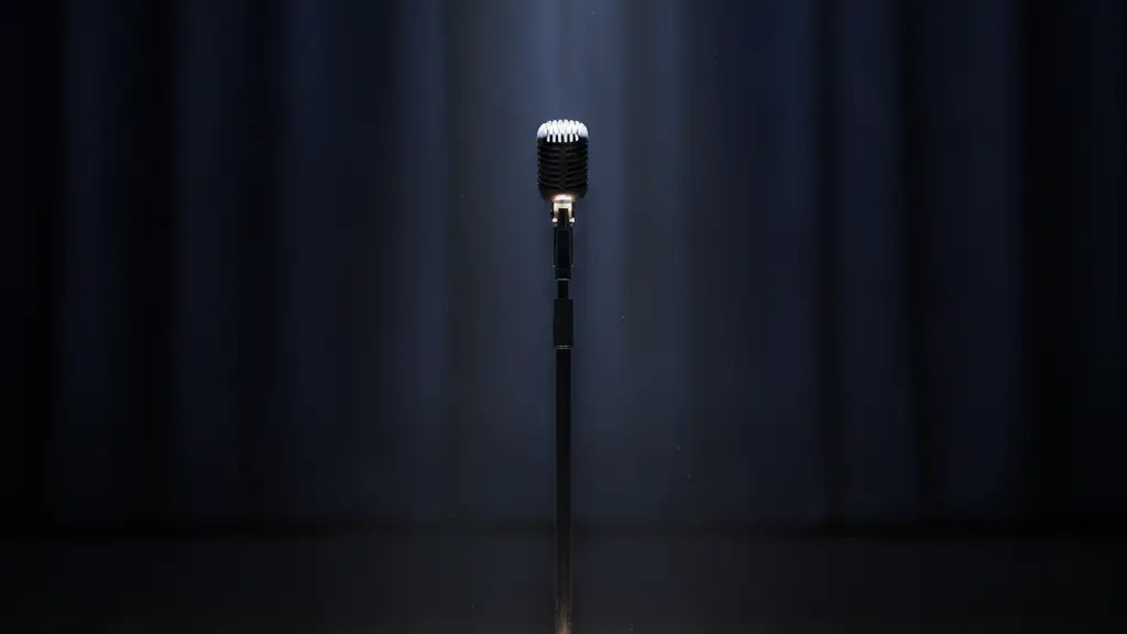 A lone microphone stand under a spotlight on an empty, dark stage.