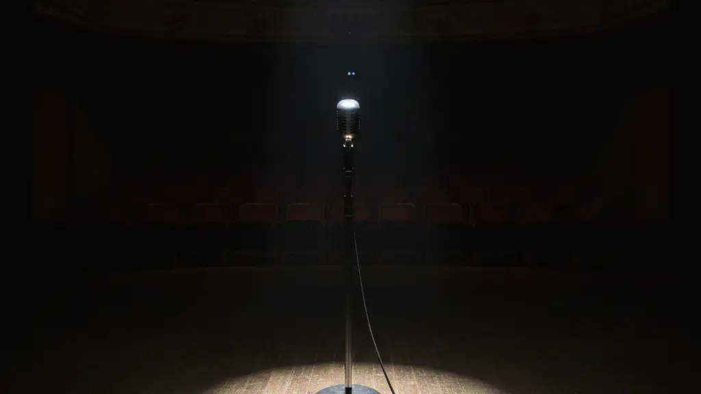 A lone vintage microphone stand under a single spotlight on an empty stage.