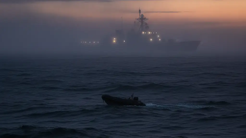 Small, dark boat on choppy sea at dawn, large naval vessel in distant mist.