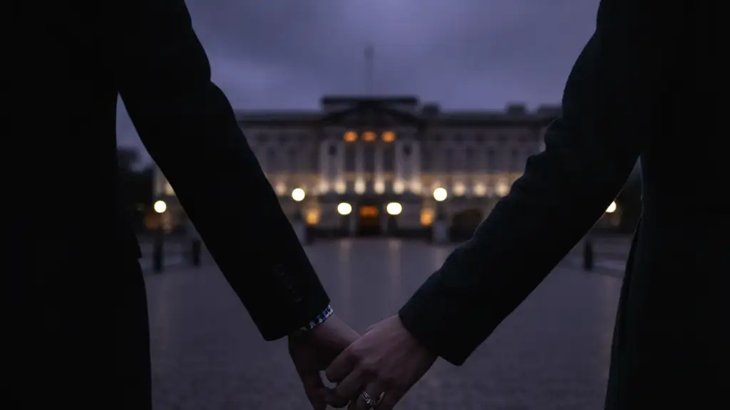 Blurred silhouettes of a couple holding hands, walking towards a distant palace at dusk.