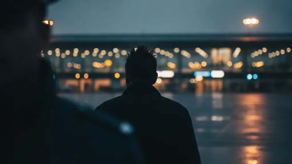 Silhouette of a man with spiky hair walking away from an airport terminal.