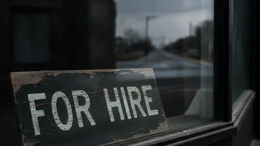 A weathered 'FOR HIRE' sign leaning against a dark, closed storefront window.