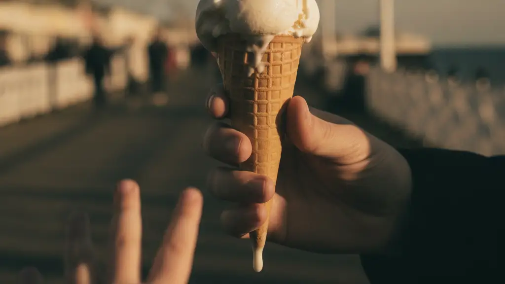 Child's hand reaching for melting ice cream cone on a sunny pier.