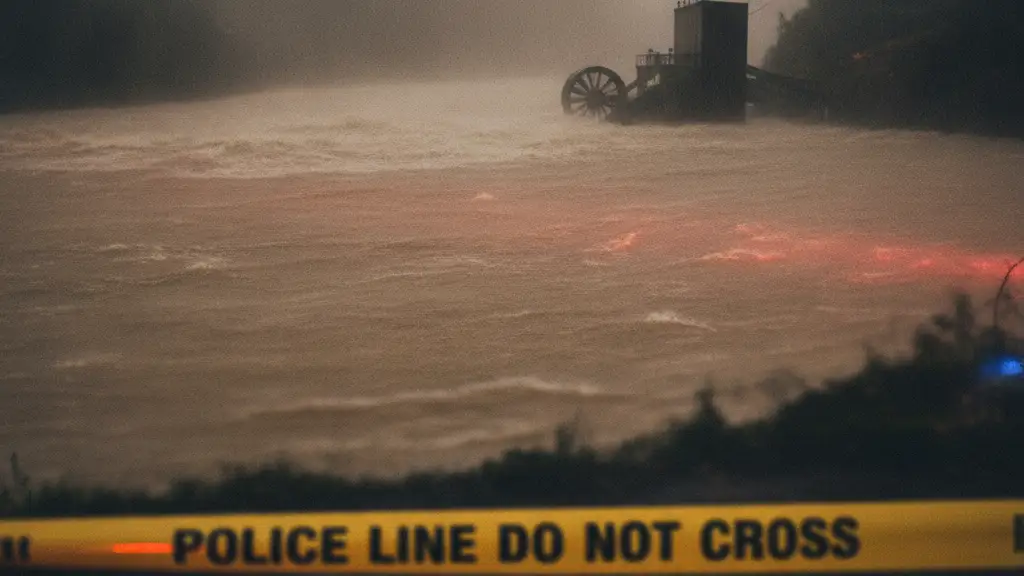 Yellow police tape in foreground, blurred raging river and distant structure in background.