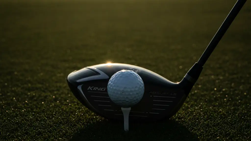 Golf club driver poised over a golf ball on a tee, blurred course background.