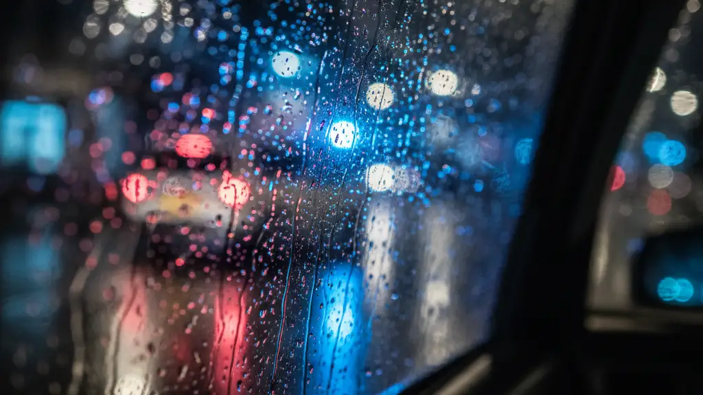 Rain-streaked taxi window at night, reflecting distant emergency lights.