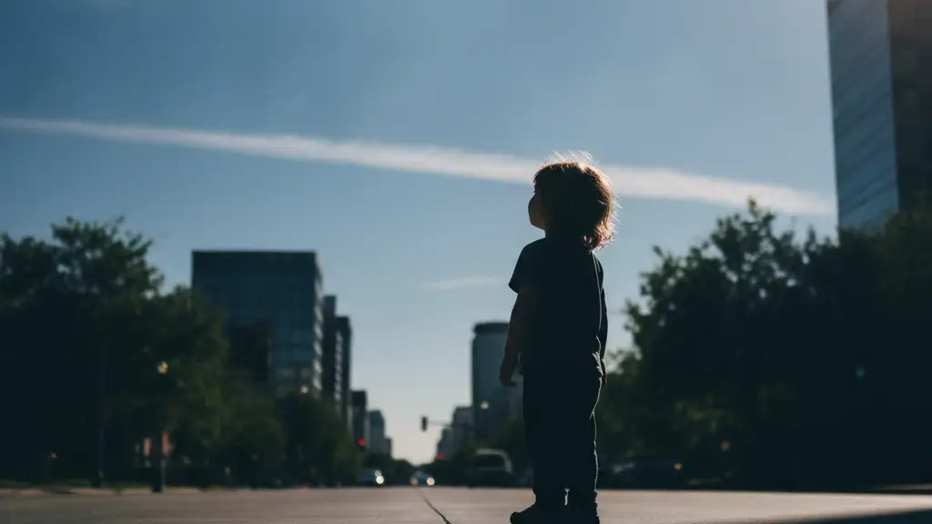 Silhouette of a child looking at a clear blue sky in a clean city.