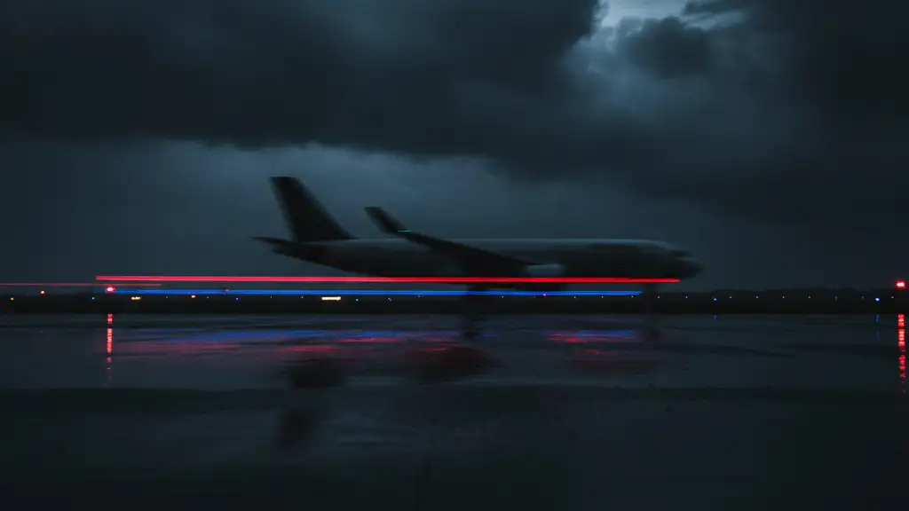 Silhouette of a passenger jet against a stormy sky with emergency lights below.