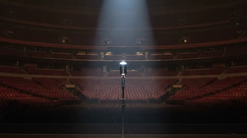 Empty Madison Square Garden stage with a single spotlight, microphone, and white rose.
