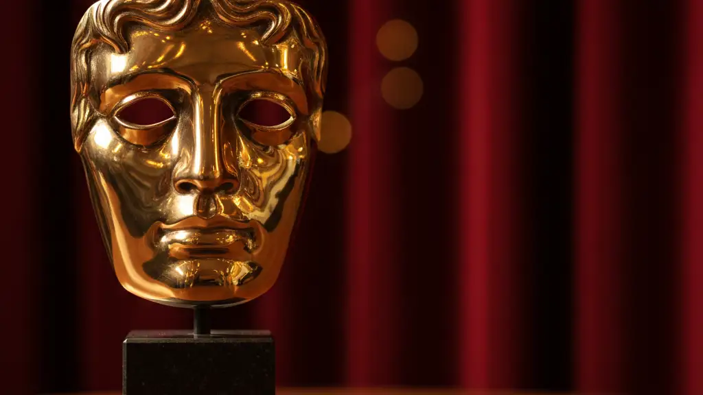 A golden BAFTA mask trophy sits on a polished surface against a blurred red background.