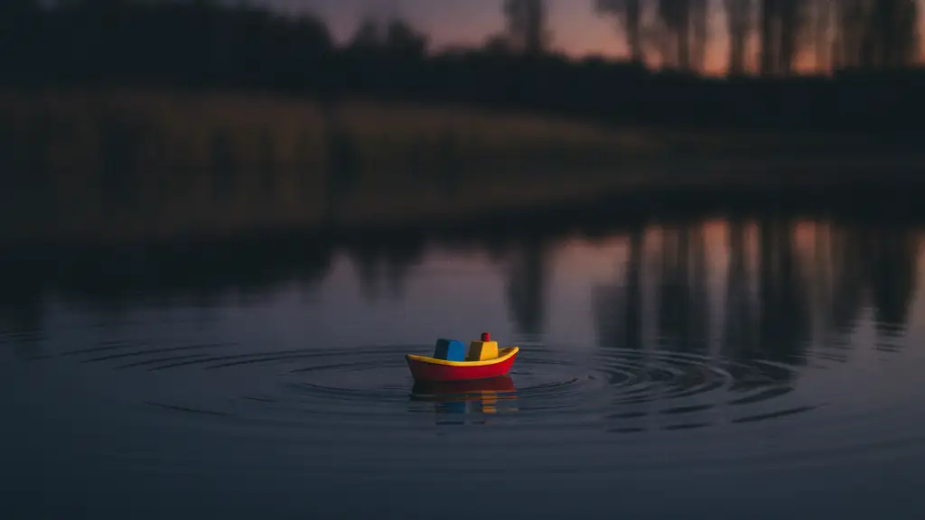 A small toy boat floats on dark, still water at twilight.