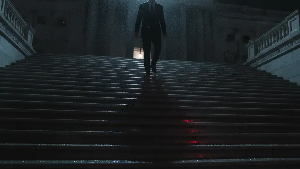 Silhouetted figure ascending grand steps, reflecting emergency lights in rain.