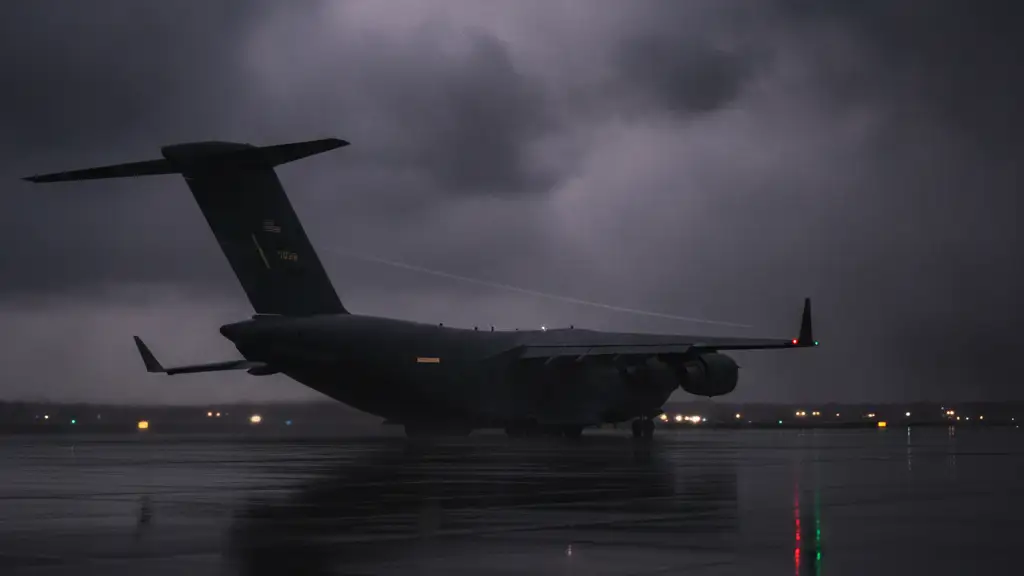 Silhouette of a large military transport plane against a stormy, dark sky at dusk.
