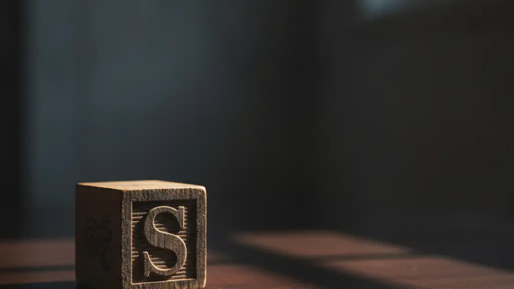 A single wooden toy block with the letter 'S' on a dark, polished surface.