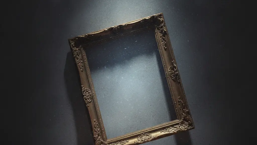 Empty ornate gold picture frame leaning against a dark museum wall.