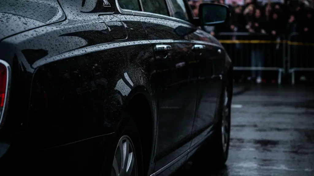 A police line tape in front of a blurred royal motorcade with emergency light reflections.