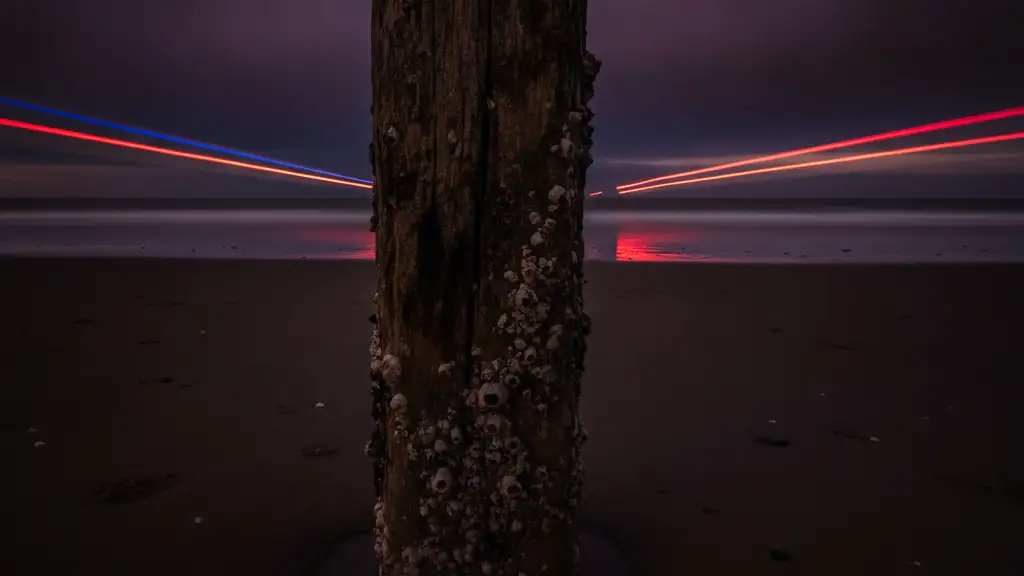 Wet sand and pier piling on Brighton beach with distant emergency lights.