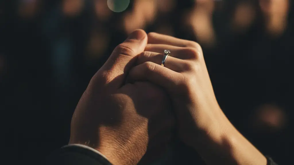Two hands, male and female, intertwined, with a ring visible.