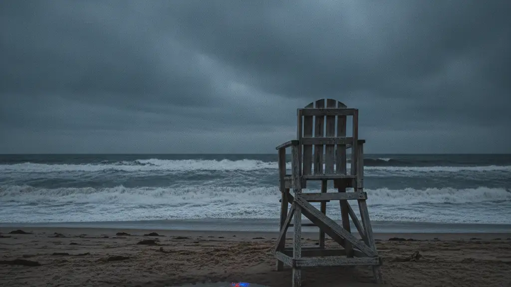 Empty lifeguard chair on a dark, stormy beach at dusk.