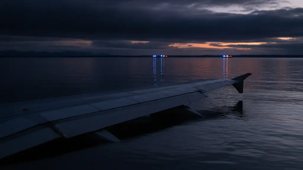 Partially submerged small plane wing in dark Alaskan waters at dusk.