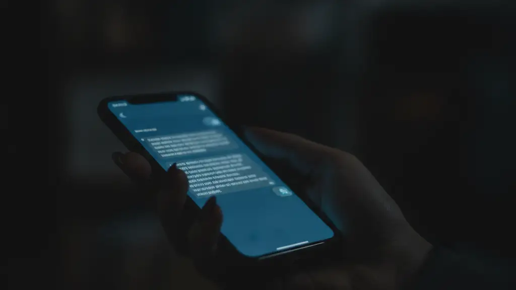 A hand holds a smartphone displaying blurred, unreadable text messages on screen.