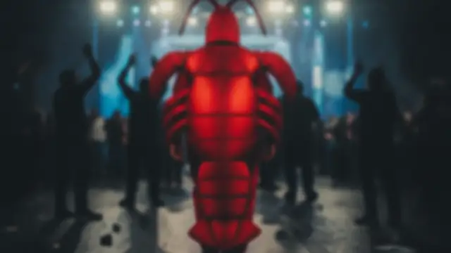 A blurry figure in a red lobster costume walks away from a darts crowd.