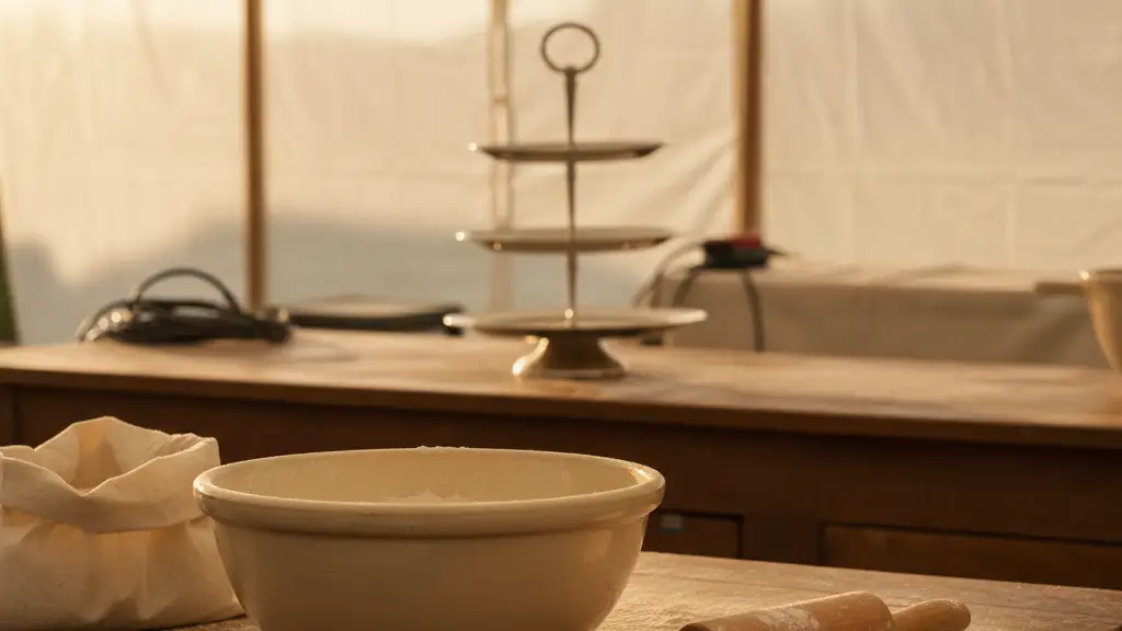 A flour-dusted baking station with a rolling pin and empty cake stand in a tent.