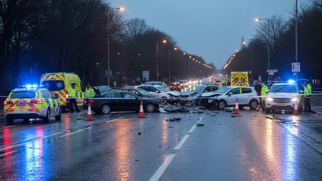 Emergency vehicles with flashing lights at a multi-vehicle crash scene on a road at night.