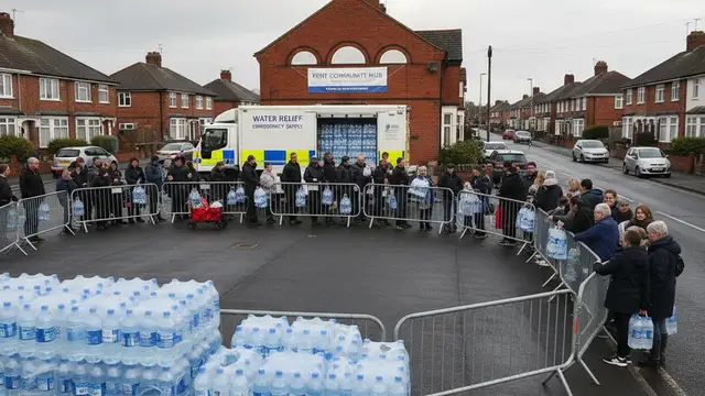 Residents collect packs of bottled water from a distribution point during a major water outage.