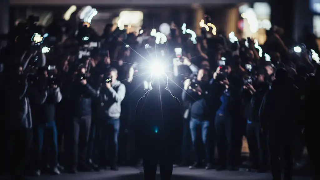 Silhouette of a person facing away, illuminated by a camera flash, amidst a blurred crowd.